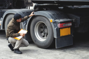 Truck driver inspecting safety check a truck tires