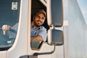 Happy truck driver looking through side window while driving his truck